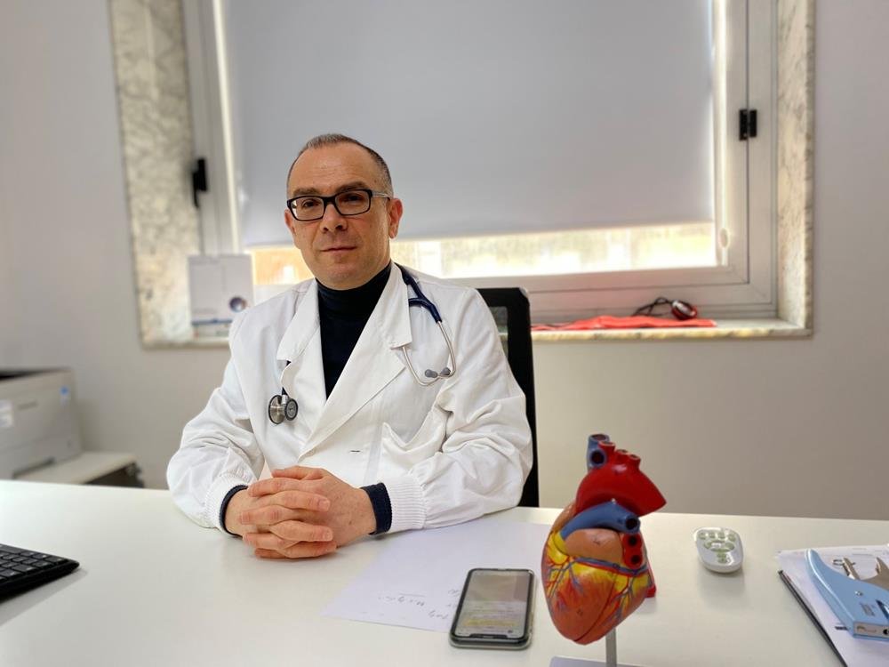 Il cardiologo a Cagliari alla scrivania dello studio con il modello anatomico del cuore
